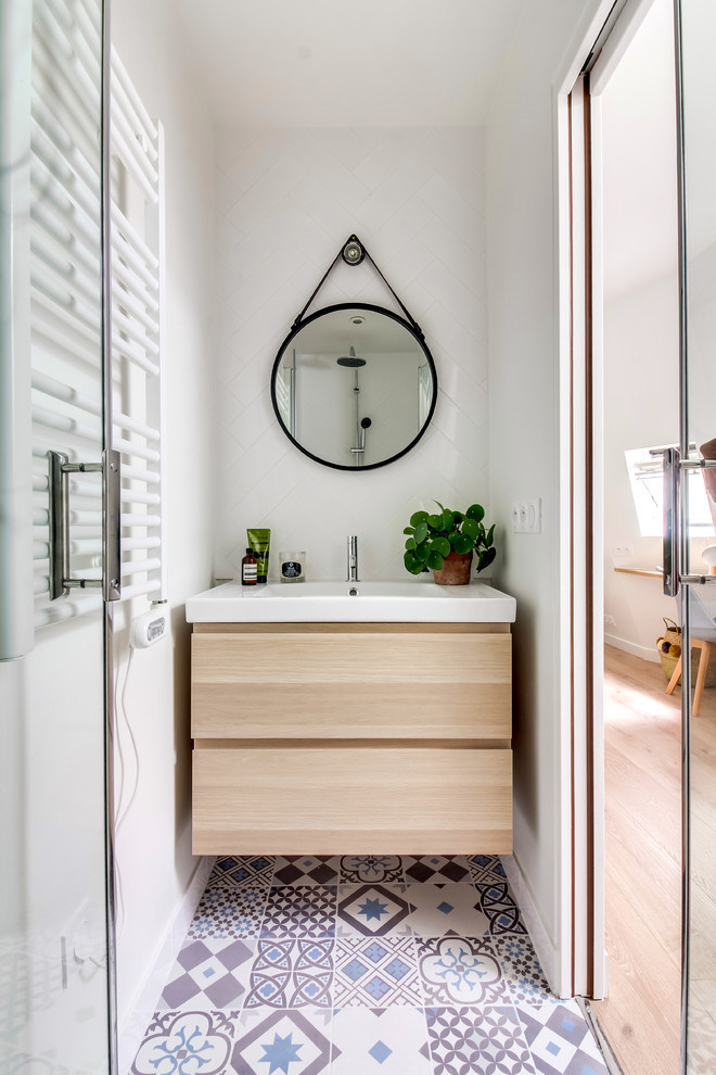 На фото: ванная комната в современном стиле с плоскими фасадами, светлыми деревянными фасадами, белой плиткой, белыми стенами, душевой кабиной, консольной раковиной и разноцветным полом с