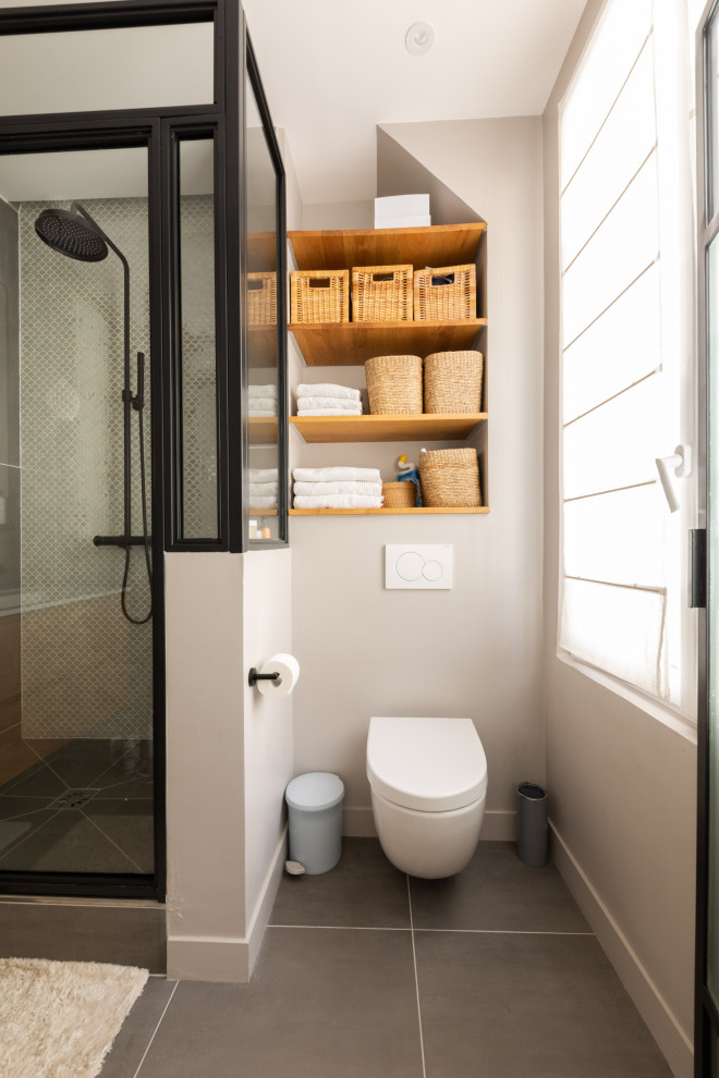 Ejemplo de cuarto de baño único y flotante nórdico de tamaño medio con armarios con paneles lisos, puertas de armario de madera clara, bañera exenta, combinación de ducha y bañera, sanitario de pared, baldosas y/o azulejos grises, baldosas y/o azulejos de cerámica, paredes grises, suelo de baldosas de cerámica, aseo y ducha, lavabo sobreencimera, encimera de acrílico, suelo gris, ducha abierta, encimeras blancas y hornacina