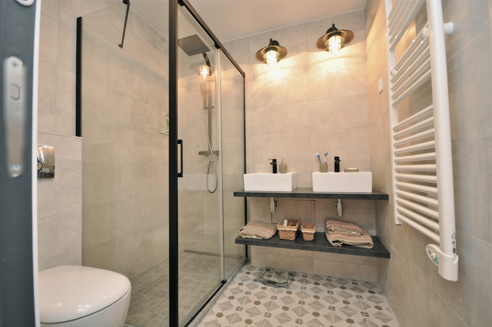 This is an example of a small industrial ensuite bathroom in Lyon with a built-in shower, beige tiles, ceramic tiles, beige walls, cement flooring, a built-in sink, tiled worktops, beige floors, a sliding door, open cabinets, black cabinets and a one-piece toilet.