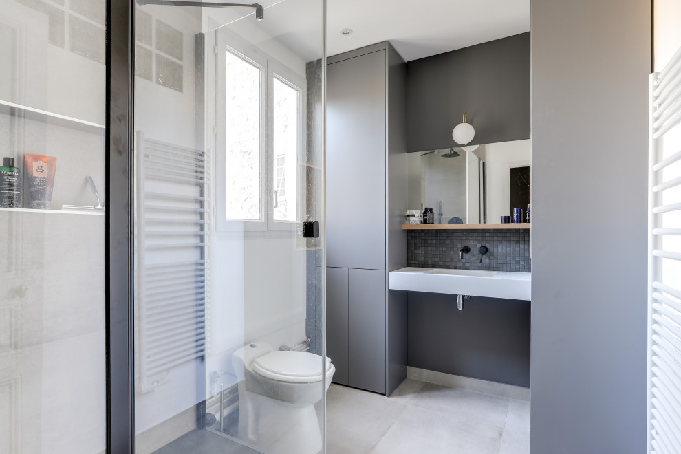 Mittelgroßes Modernes Duschbad mit flächenbündigen Schrankfronten, grauen Schränken, grauen Fliesen, Waschtischkonsole und weißer Waschtischplatte in Paris