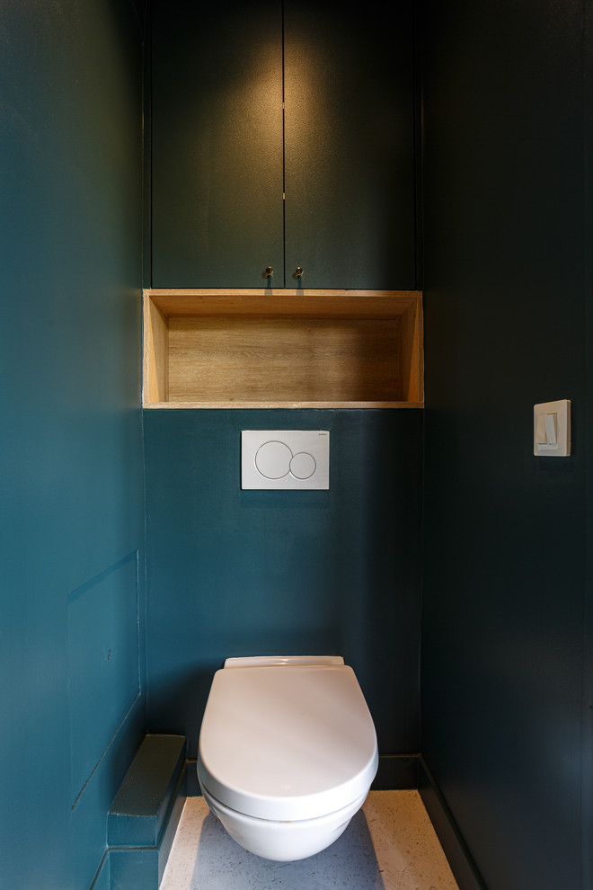 Пример оригинального дизайна: туалет среднего размера в скандинавском стиле с плоскими фасадами, светлыми деревянными фасадами, инсталляцией, белой плиткой, керамогранитной плиткой, синими стенами, полом из терраццо, подвесной раковиной, столешницей из искусственного камня, серым полом и белой столешницей
