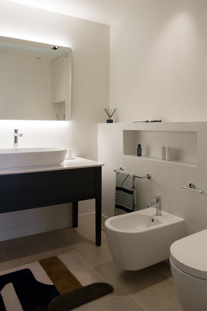 На фото: главная ванная комната в современном стиле с синими фасадами, биде, белыми стенами, настольной раковиной, бежевым полом, белой столешницей и плоскими фасадами