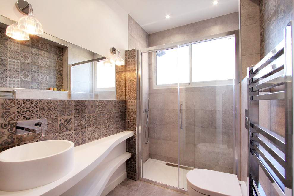 Foto di una stanza da bagno minimal con lavabo a bacinella, nessun'anta, WC monopezzo e piastrelle grigie