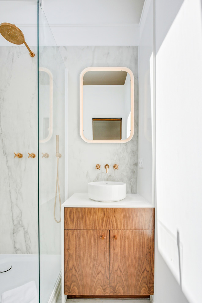 Modernes Duschbad mit flächenbündigen Schrankfronten, hellbraunen Holzschränken, weißen Fliesen, Steinplatten, weißer Wandfarbe, Aufsatzwaschbecken und weißer Waschtischplatte in Paris