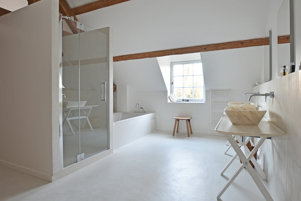 На фото: большая главная ванная комната в скандинавском стиле с ванной в нише, белыми стенами, настольной раковиной, белой плиткой, плиткой из листового камня, бетонным полом и мраморной столешницей