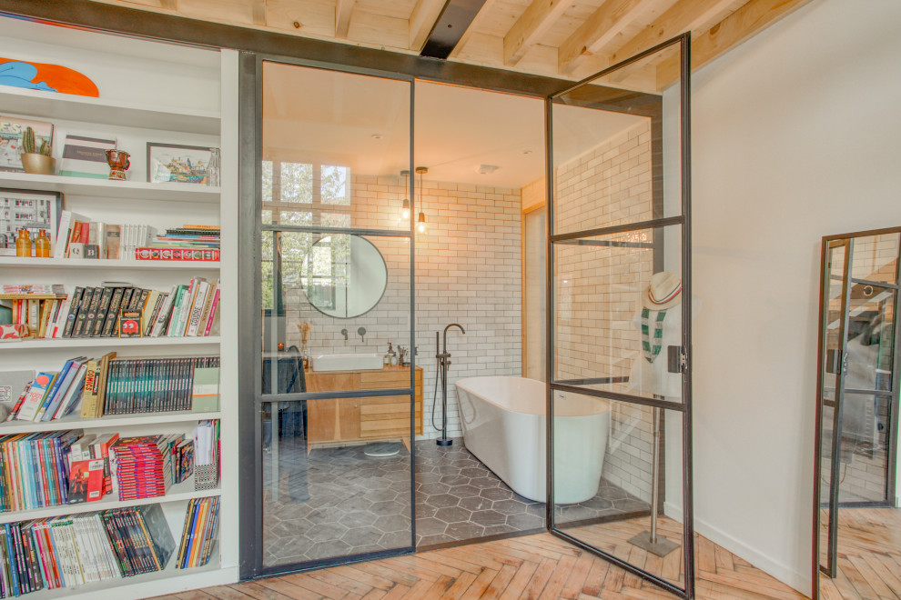 Cette photo montre une salle de bain tendance en bois brun avec un placard à porte plane, une baignoire indépendante, un carrelage blanc, une vasque, un plan de toilette en bois, un sol gris, un plan de toilette marron, meuble simple vasque et meuble-lavabo sur pied.
