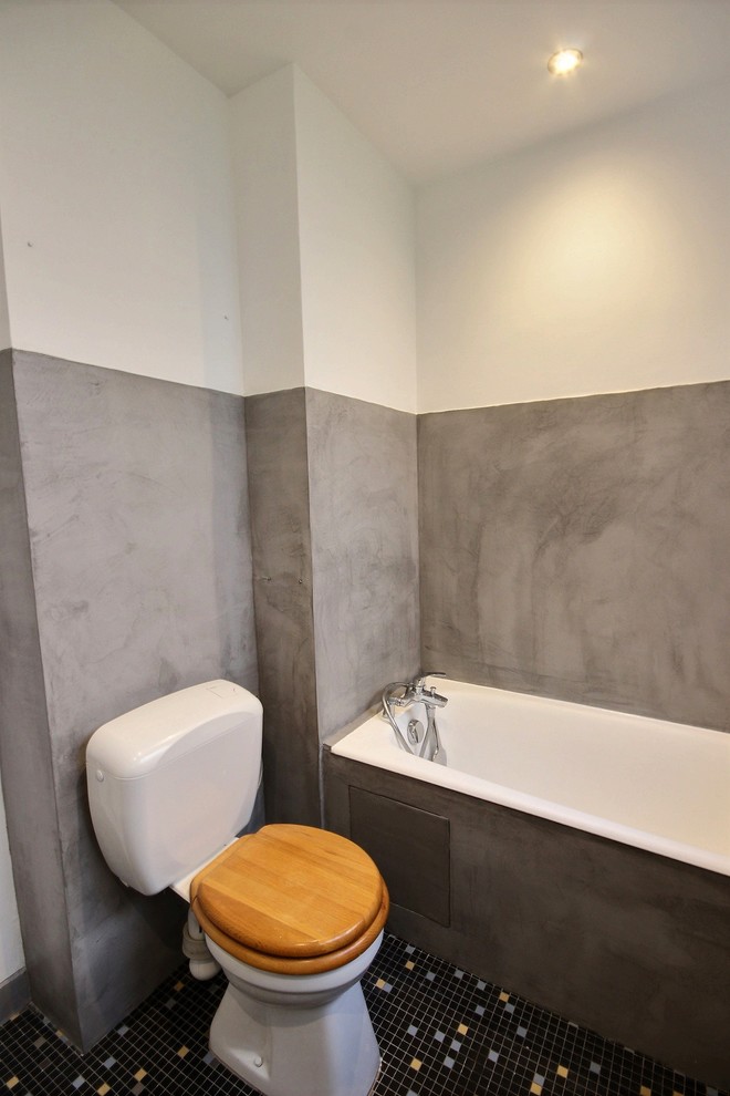 Réalisation d'une grande salle de bain principale minimaliste avec une baignoire encastrée, WC à poser, un carrelage gris, un mur gris, un sol en carrelage de terre cuite, un lavabo de ferme, un sol noir et un plan de toilette blanc.