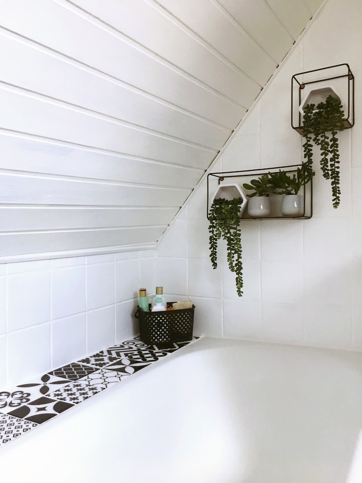 Cette image montre une petite salle d'eau vintage avec des portes de placard beiges, une baignoire encastrée, un carrelage blanc, des carreaux de céramique, un mur blanc, un sol en vinyl, un lavabo encastré, un plan de toilette en stratifié, un sol beige et un plan de toilette noir.