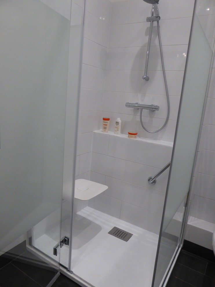 Exempel på ett litet modernt badrum med dusch, med vit kakel, keramikplattor, vita väggar, klinkergolv i keramik, svart golv och dusch med gångjärnsdörr