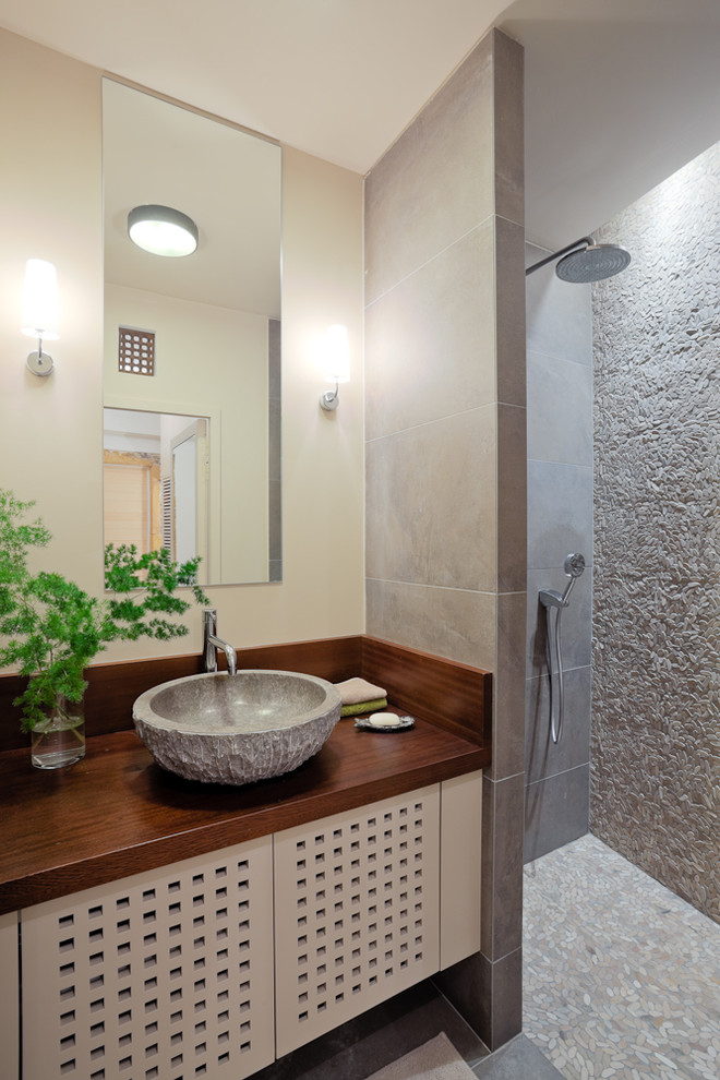 Diseño de cuarto de baño asiático pequeño con aseo y ducha, ducha a ras de suelo, baldosas y/o azulejos beige, paredes beige, lavabo sobreencimera, encimera de madera y encimeras marrones