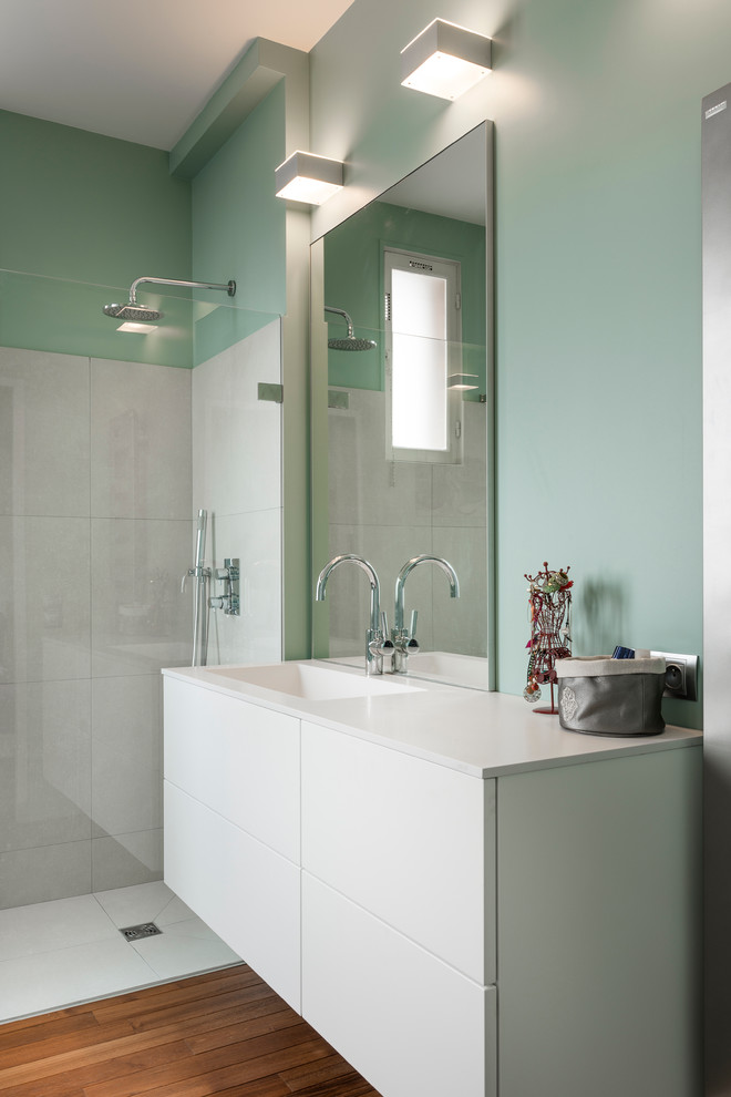 Modelo de cuarto de baño contemporáneo con ducha a ras de suelo, baldosas y/o azulejos beige, baldosas y/o azulejos de cerámica, paredes verdes, suelo de madera clara y encimera de acrílico