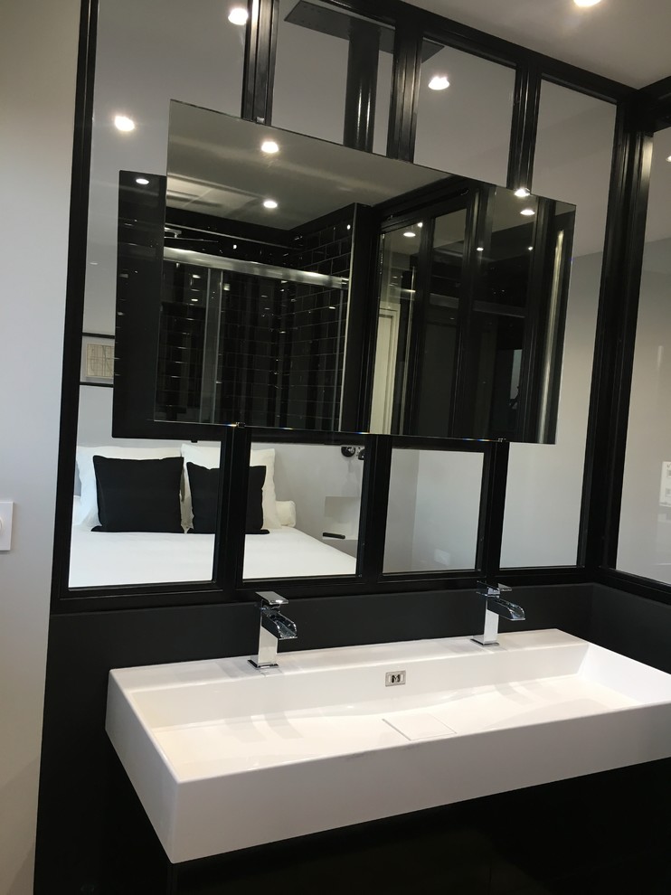 Bild på ett litet funkis vit vitt badrum med dusch, med luckor med profilerade fronter, svarta skåp, en dubbeldusch, en vägghängd toalettstol, svart kakel, tunnelbanekakel, grå väggar, plywoodgolv, ett avlångt handfat, marmorbänkskiva, brunt golv och dusch med skjutdörr