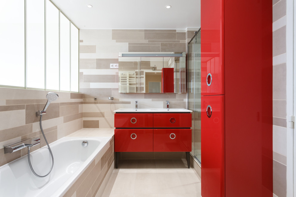 Foto på ett funkis vit badrum, med röda skåp, ett platsbyggt badkar, en dusch i en alkov, beiget golv, dusch med skjutdörr och släta luckor