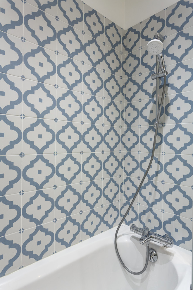 Kleines Modernes Badezimmer En Suite mit flächenbündigen Schrankfronten, beigen Schränken, Einbaubadewanne, Duschbadewanne, Wandtoilette mit Spülkasten, blauen Fliesen, Keramikfliesen, weißer Wandfarbe, Keramikboden, Waschtischkonsole, Mineralwerkstoff-Waschtisch, blauem Boden, Falttür-Duschabtrennung und weißer Waschtischplatte in Paris