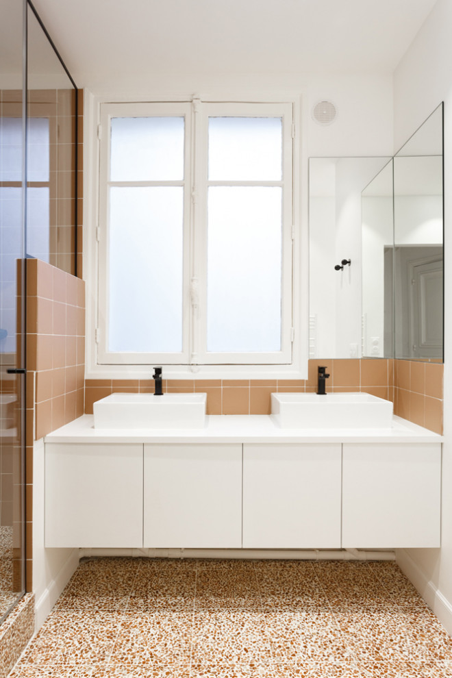 Пример оригинального дизайна: главная ванная комната среднего размера в стиле модернизм с фасадами с декоративным кантом, белыми фасадами, накладной ванной, душем над ванной, инсталляцией, зеленой плиткой, керамогранитной плиткой, белыми стенами, полом из керамогранита, накладной раковиной, столешницей из искусственного камня, разноцветным полом, душем с распашными дверями, белой столешницей, тумбой под две раковины и напольной тумбой