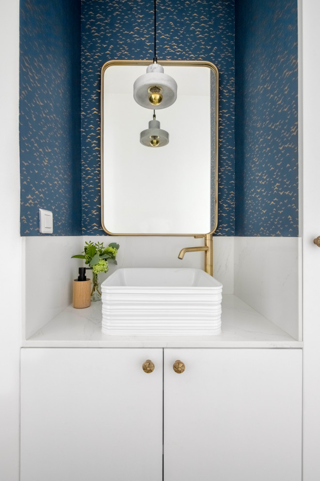 Aménagement d'un WC et toilettes contemporain avec un placard à porte plane, des portes de placard blanches, un mur bleu, une vasque, un plan de toilette blanc, meuble-lavabo encastré et du papier peint.