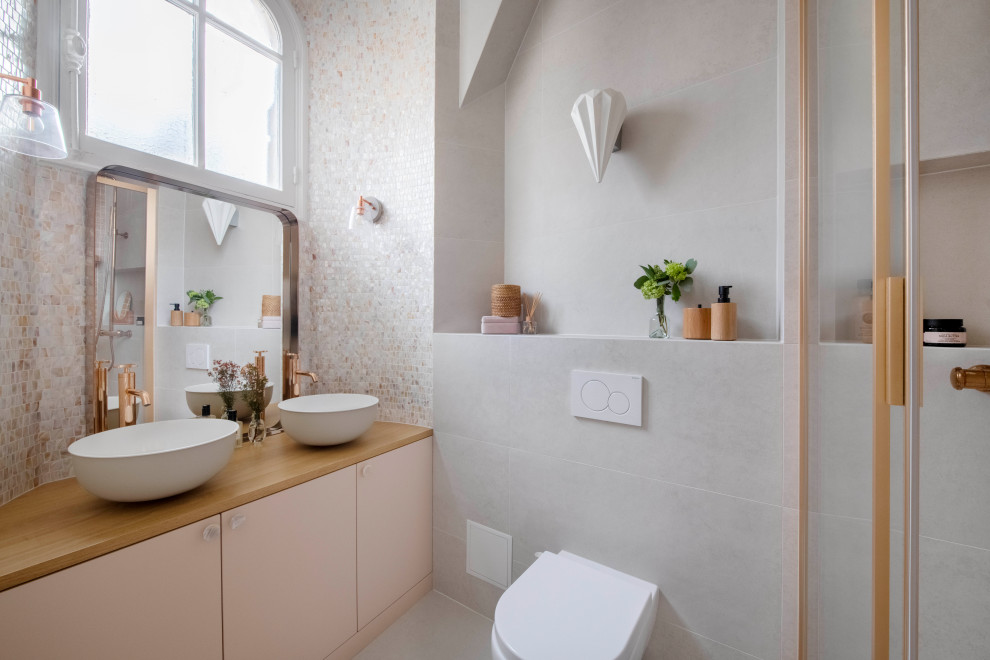 Cette photo montre une salle d'eau grise et rose tendance avec un placard à porte plane, un carrelage gris, une vasque, un plan de toilette en bois, un sol gris, un plan de toilette marron, meuble double vasque et meuble-lavabo encastré.