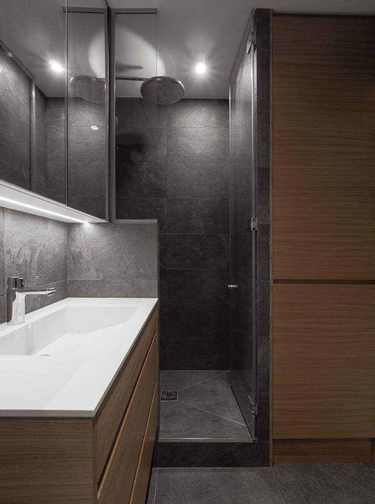 На фото: маленькая главная ванная комната в стиле модернизм с фасадами с декоративным кантом, светлыми деревянными фасадами, душем в нише, инсталляцией, серой плиткой, плиткой из сланца, серыми стенами, полом из керамической плитки, врезной раковиной, столешницей из искусственного камня, серым полом, душем с распашными дверями, белой столешницей, тумбой под одну раковину и подвесной тумбой для на участке и в саду с