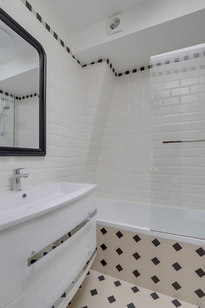 Cette image montre une salle d'eau design avec une baignoire encastrée, un carrelage blanc, un carrelage métro, un mur blanc, carreaux de ciment au sol et un sol blanc.