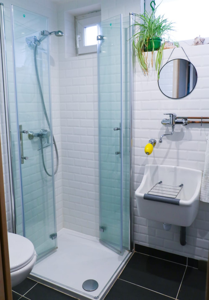 Exempel på ett litet lantligt badrum med dusch, med en hörndusch, en vägghängd toalettstol, vit kakel, tunnelbanekakel, vita väggar, klinkergolv i keramik, ett väggmonterat handfat, grått golv och dusch med gångjärnsdörr