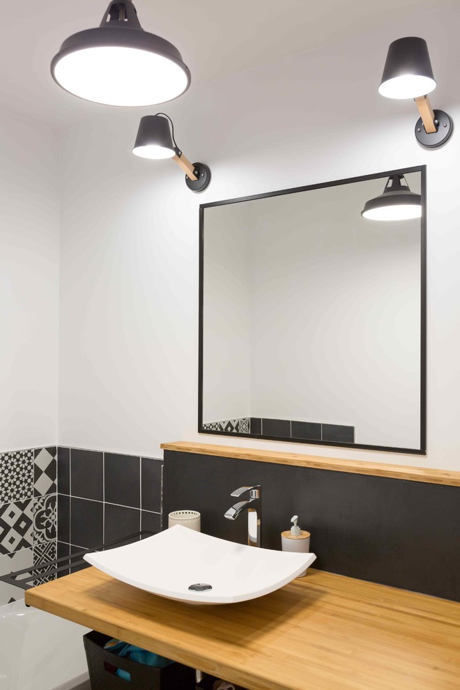 Idée de décoration pour une petite salle de bain design avec une baignoire encastrée, un carrelage noir et blanc, des carreaux de béton, un mur blanc, un sol en bois brun et une vasque.