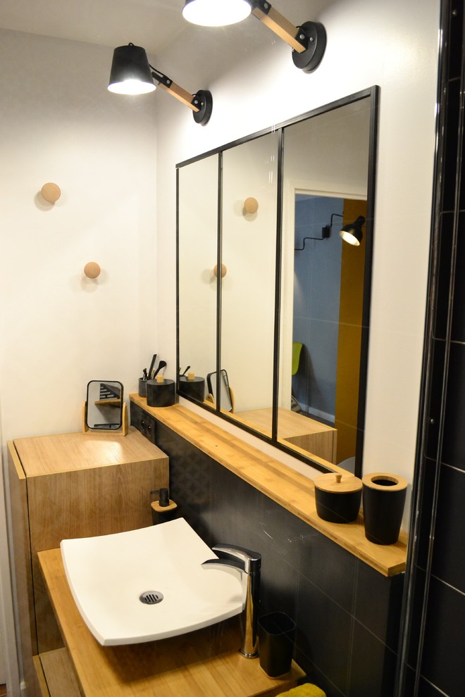Cette photo montre une salle de bain principale tendance de taille moyenne avec une douche ouverte, WC suspendus, un carrelage noir et blanc, des carreaux de béton, un mur blanc, un sol en bois brun, un lavabo posé et un plan de toilette en bois.