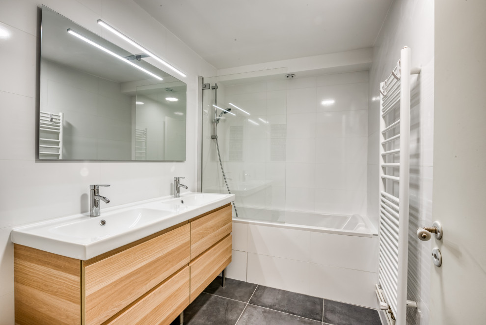 パリにある低価格の小さなコンテンポラリースタイルのおしゃれなマスターバスルーム (大型浴槽、白いタイル、白い壁、セラミックタイルの床、アンダーカウンター洗面器、グレーの床、白い洗面カウンター、フラットパネル扉のキャビネット、ベージュのキャビネット、シャワー付き浴槽	) の写真