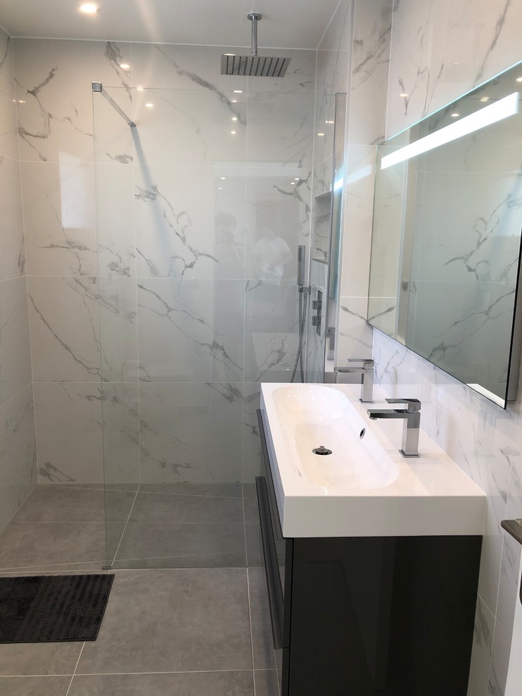 Idéer för ett mellanstort en-suite badrum, med en kantlös dusch, en vägghängd toalettstol, svart och vit kakel, marmorkakel, vita väggar, cementgolv, ett avlångt handfat och grått golv