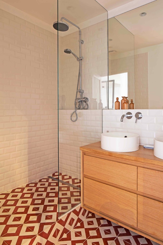 Bild på ett litet funkis badrum med dusch, med luckor med profilerade fronter, skåp i ljust trä, en kantlös dusch, röd kakel, tunnelbanekakel, vita väggar, cementgolv, ett fristående handfat och träbänkskiva