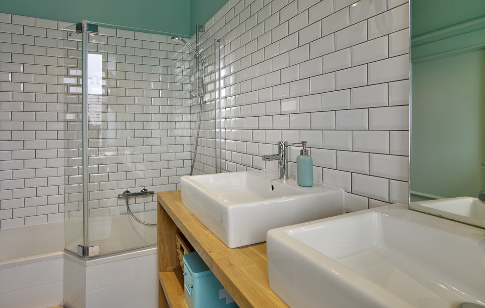 Ejemplo de cuarto de baño nórdico de tamaño medio con combinación de ducha y bañera, baldosas y/o azulejos blancos, baldosas y/o azulejos de cemento, paredes verdes, suelo laminado y lavabo encastrado