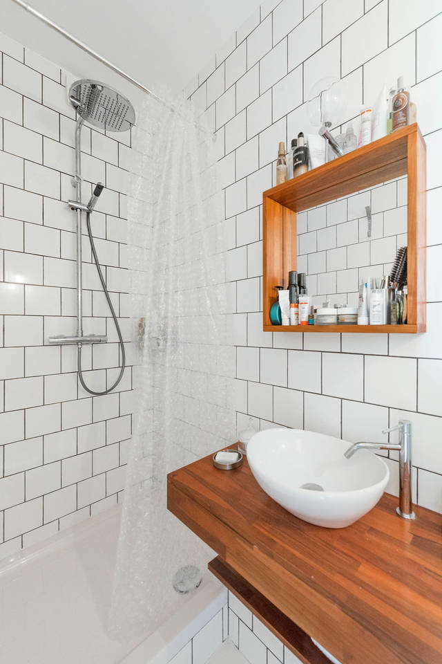 Cette image montre une salle de bain principale design avec des portes de placard marrons, une baignoire d'angle, un espace douche bain, un carrelage blanc, des carreaux en allumettes, un mur blanc, une grande vasque, un plan de toilette en bois et une cabine de douche avec un rideau.