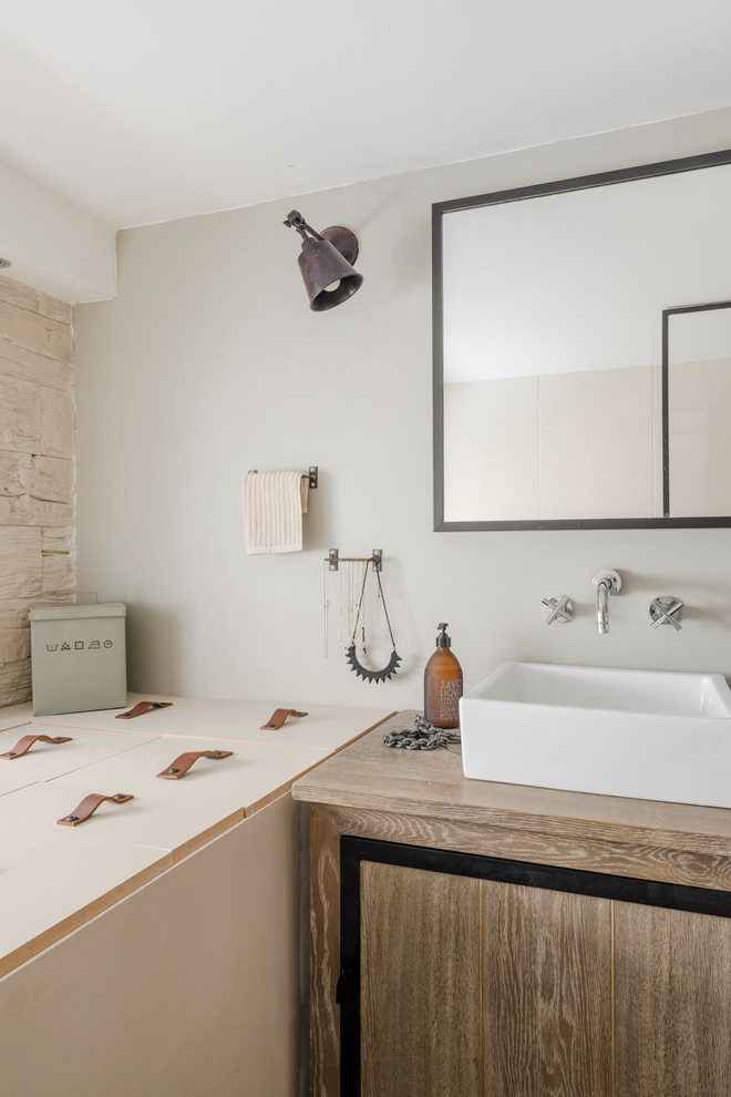 Modelo de cuarto de baño principal urbano con lavabo sobreencimera, encimera de madera, baldosas y/o azulejos beige, paredes grises y suelo de madera oscura
