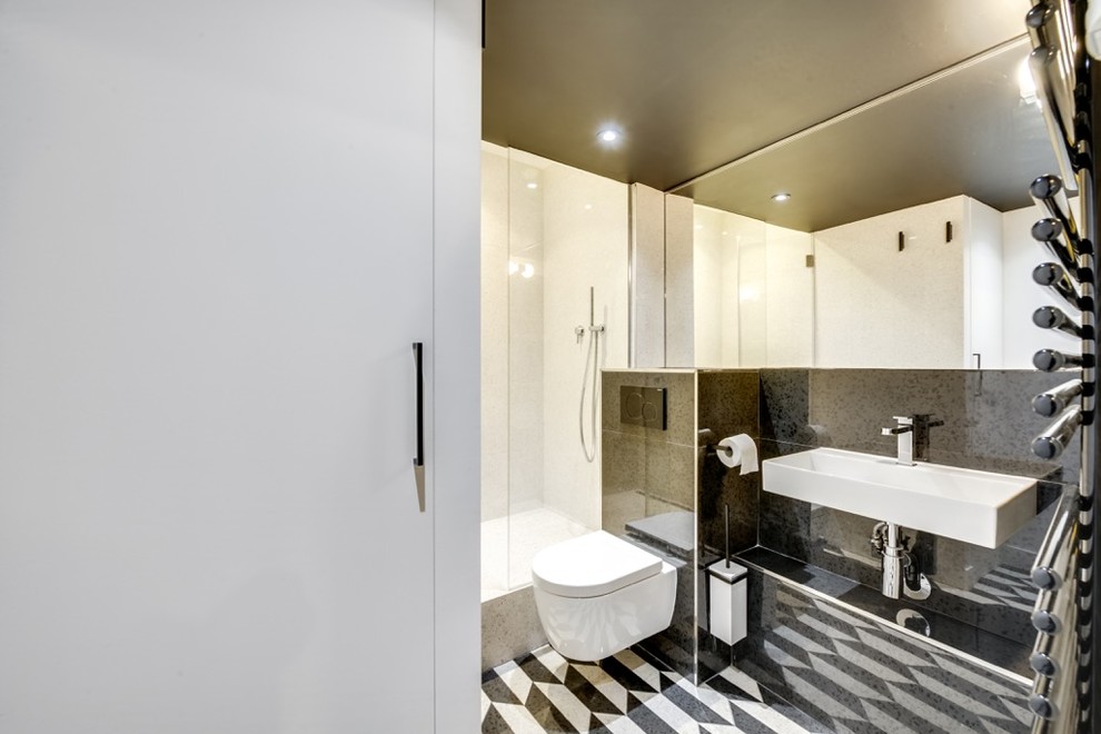 Foto på ett litet funkis vit en-suite badrum, med en dusch i en alkov, en vägghängd toalettstol, svart kakel, svarta väggar, cementgolv, ett väggmonterat handfat och svart golv