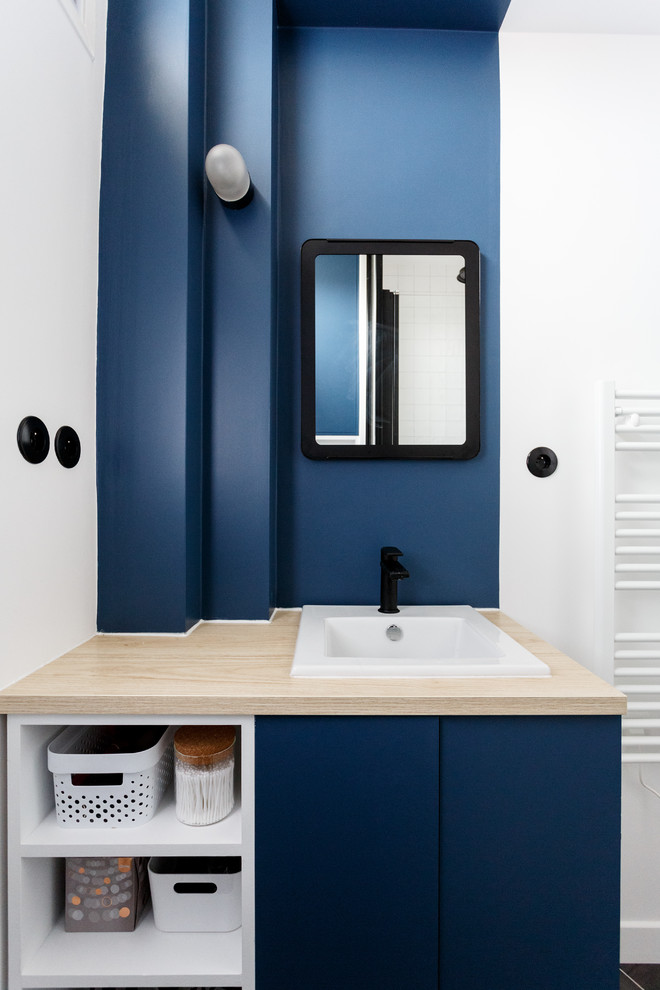 Источник вдохновения для домашнего уюта: маленькая главная ванная комната в стиле модернизм с плоскими фасадами, синими фасадами, душем без бортиков, инсталляцией, белой плиткой, керамической плиткой, синими стенами, полом из керамической плитки, накладной раковиной, столешницей из дерева, серым полом, душем с распашными дверями и бежевой столешницей для на участке и в саду