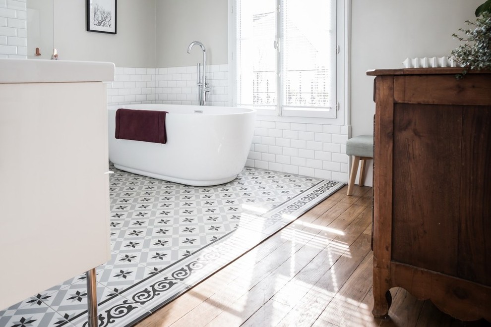 Idéer för mellanstora vintage en-suite badrum, med släta luckor, vita skåp, en kantlös dusch, vit kakel, tunnelbanekakel, grå väggar, cementgolv, ett avlångt handfat, bänkskiva i akrylsten, grått golv, med dusch som är öppen och ett fristående badkar