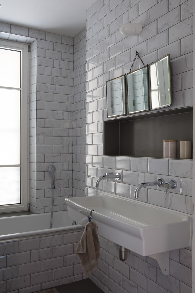 Cette image montre une salle de bain bohème de taille moyenne pour enfant avec une baignoire posée, WC suspendus, un carrelage gris, du carrelage en marbre, un mur gris, carreaux de ciment au sol, un lavabo suspendu et un sol gris.