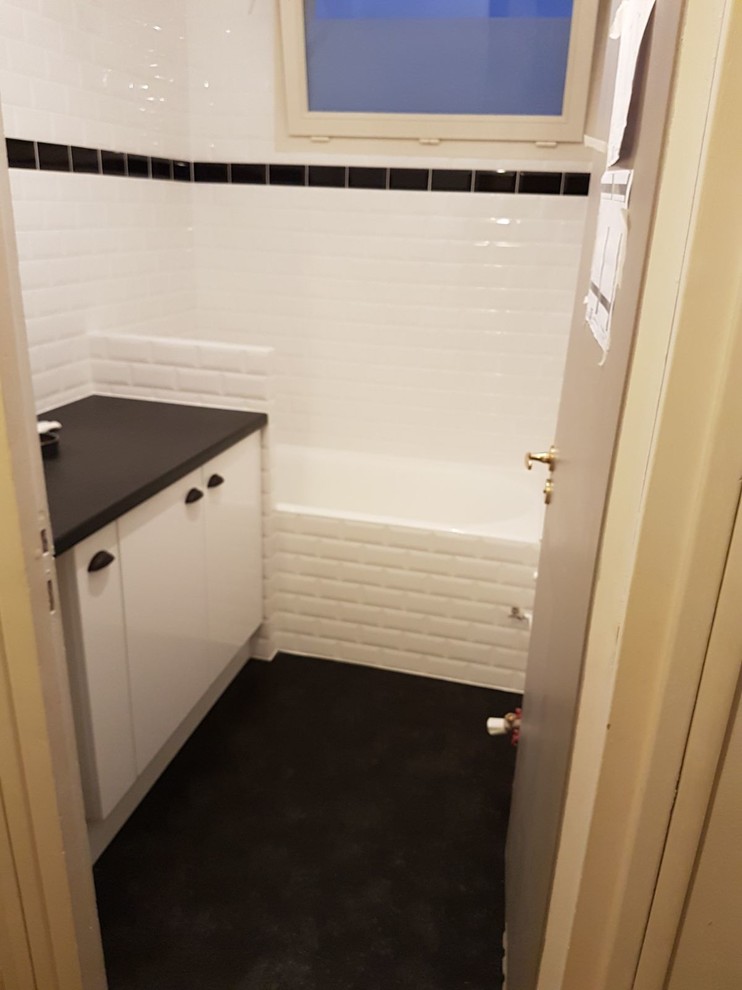 Photo of a small retro ensuite bathroom in Paris with flat-panel cabinets, white cabinets, a built-in bath, white tiles, metro tiles, vinyl flooring, a vessel sink, laminate worktops, black floors and black worktops.