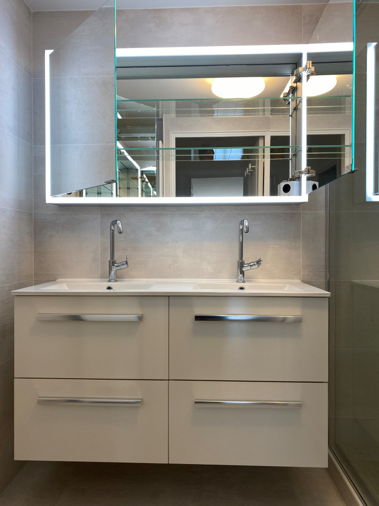 Exempel på ett litet modernt vit vitt en-suite badrum, med släta luckor, beige skåp, en kantlös dusch, grå kakel, keramikplattor, grå väggar, klinkergolv i keramik, ett väggmonterat handfat, bänkskiva i kvarts och grått golv