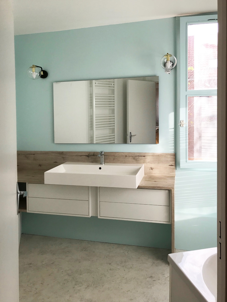 Réalisation d'une petite salle de bain principale design avec des portes de placard blanches, une baignoire indépendante, un mur bleu, un sol en linoléum, un lavabo posé, un plan de toilette en stratifié et un sol gris.