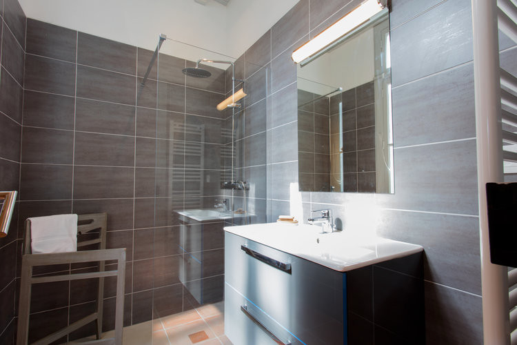 Esempio di una piccola stanza da bagno padronale con ante grigie, doccia a filo pavimento, piastrelle grigie, lavabo integrato, doccia aperta, pareti grigie, top in superficie solida, pavimento arancione e top bianco