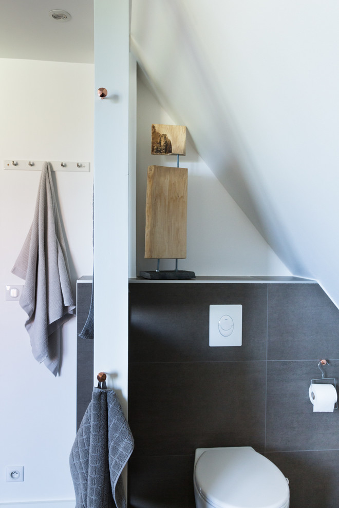 Foto på ett mellanstort funkis en-suite badrum, med ett fristående handfat, släta luckor, vita skåp, träbänkskiva, ett undermonterat badkar, en kantlös dusch, en vägghängd toalettstol, brun kakel, keramikplattor, vita väggar och ljust trägolv