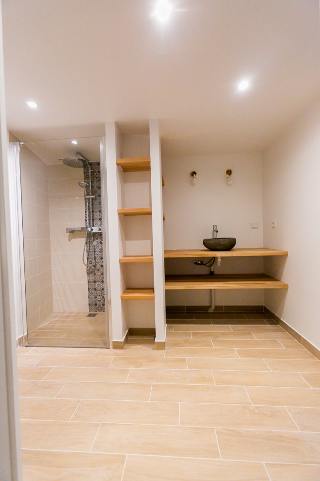 Exempel på ett modernt badrum med dusch, med skåp i ljust trä, en kantlös dusch, en toalettstol med hel cisternkåpa, ett nedsänkt handfat, träbänkskiva, beiget golv och dusch med gångjärnsdörr