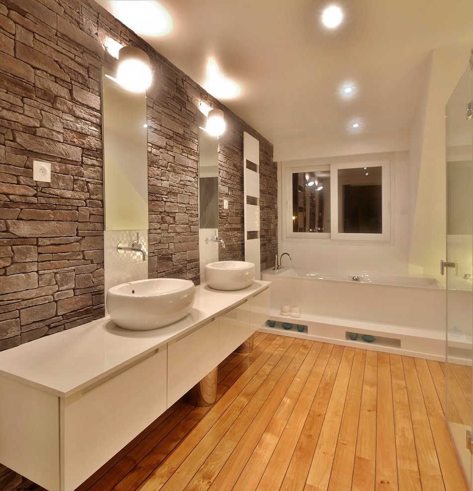 Foto på ett mycket stort funkis en-suite badrum, med ett nedsänkt handfat, luckor med profilerade fronter, vita skåp, bänkskiva i akrylsten, ett platsbyggt badkar, en kantlös dusch, grå kakel, stenkakel, vita väggar och ljust trägolv