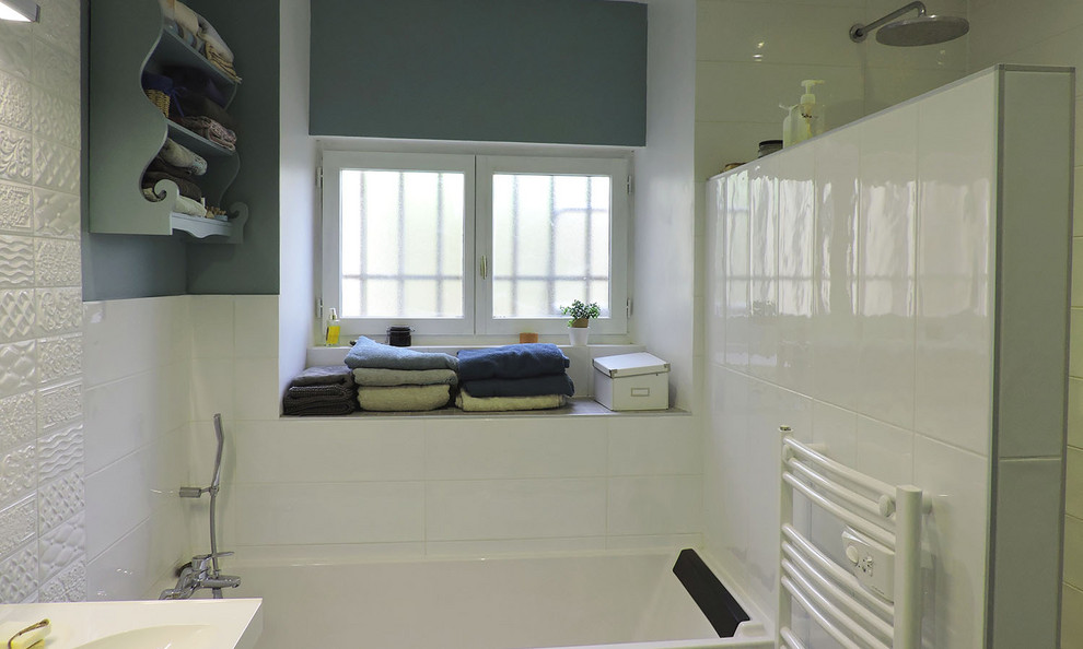 Badezimmer mit Unterbauwanne, bodengleicher Dusche, weißen Fliesen, Keramikfliesen, Waschtischkonsole, grauem Boden und weißer Waschtischplatte in Grenoble