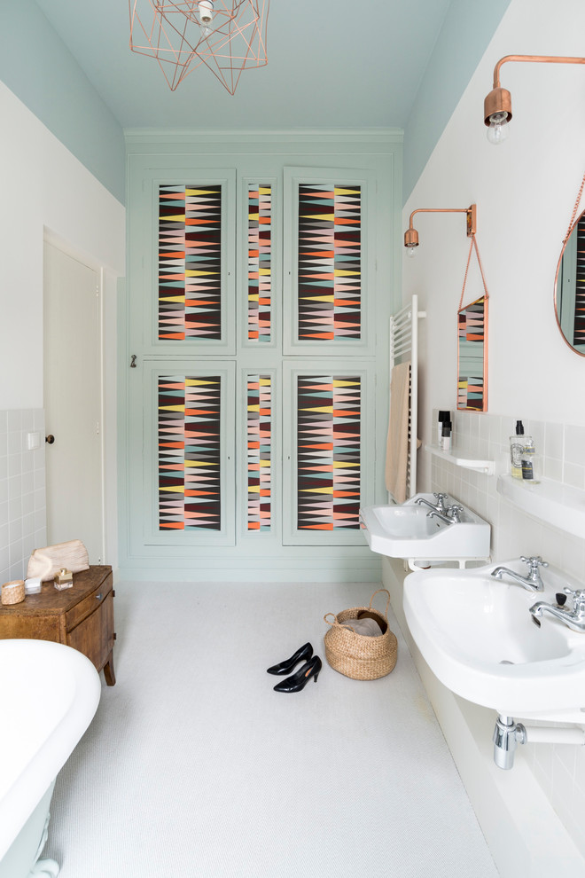 Стильный дизайн: главная ванная комната среднего размера в скандинавском стиле с ванной на ножках, белой плиткой, синими стенами, подвесной раковиной, зелеными фасадами и зеркалом с подсветкой - последний тренд