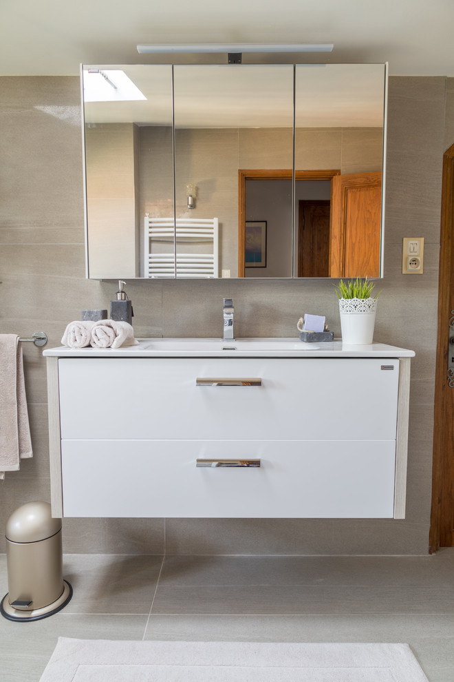 Photo of a large mediterranean ensuite bathroom in Marseille with beaded cabinets, white cabinets, beige tiles, beige walls, cement flooring, a trough sink, solid surface worktops, beige floors, a sliding door and white worktops.