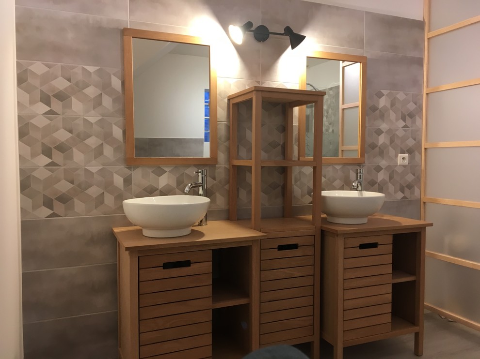 Cette photo montre une salle de bain principale tendance de taille moyenne avec un placard à porte affleurante, des portes de placard beiges, un carrelage beige, un mur beige, parquet clair, une grande vasque, un plan de toilette en bois et un sol beige.