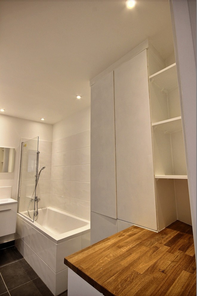 パリにあるヴィクトリアン調のおしゃれなマスターバスルーム (白いキャビネット、アンダーマウント型浴槽、白いタイル、ベッセル式洗面器、グレーの床) の写真