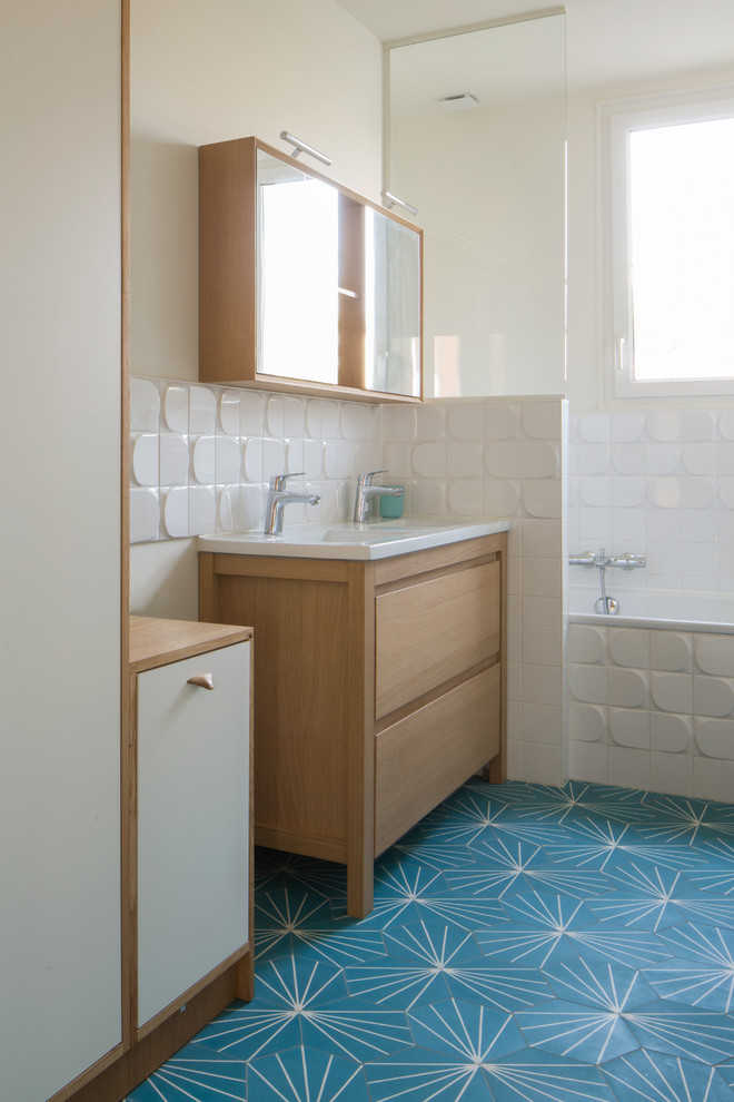 Cette photo montre une salle de bain principale tendance de taille moyenne avec un placard à porte affleurante, des portes de placard beiges, une baignoire d'angle, un combiné douche/baignoire, un carrelage blanc, des carreaux en allumettes, un mur blanc, carreaux de ciment au sol, une grande vasque, un plan de toilette en bois, un sol bleu et un plan de toilette beige.