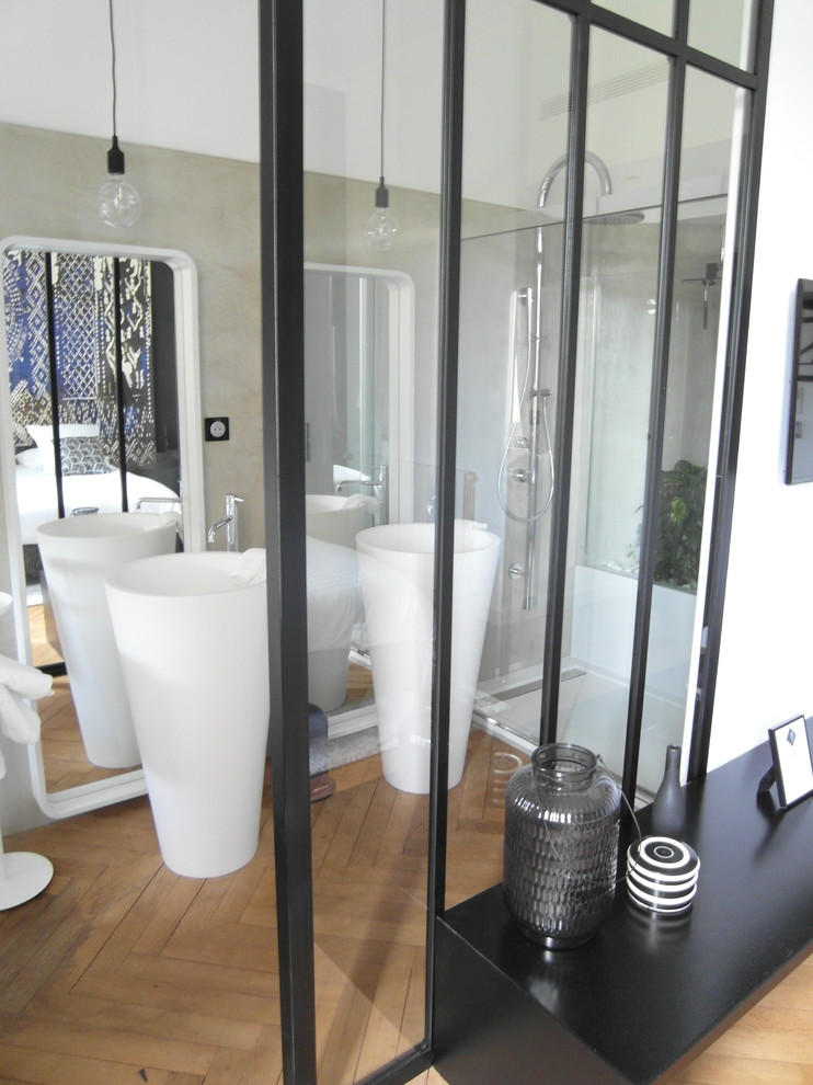 Modelo de cuarto de baño principal contemporáneo de tamaño medio con bañera encastrada, suelo de cemento, lavabo con pedestal, sanitario de pared, paredes grises y encimera de acrílico